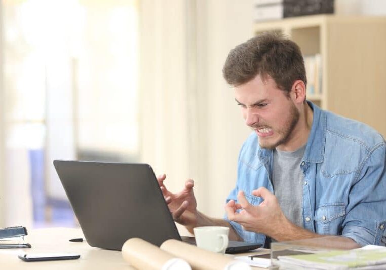 Entrepreneur angry and furious with a laptop in a little office or home